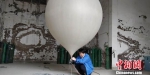 贵阳市高空气象探测站高级工程师闵昌红正在为探空气球灌装氢气 曾实 摄 - 贵州新闻